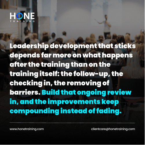 Slide from a leadership training session by Hone Training: audience listening to a speaker on stage, with bold white and blue text about ongoing reviews and improvements.